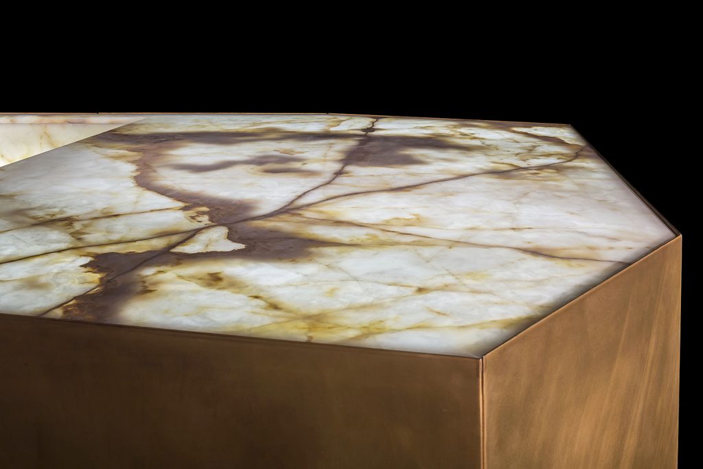 Ozone Evo kitchen bar, cover in brass, top and sink in white and brown irregluar pattern marble stone with black faucet on a black background.