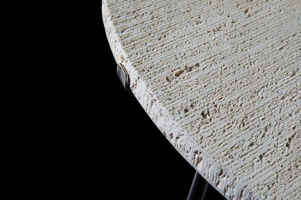 Closeup of a round Primitive Table top in white ostuni stone on a black background.