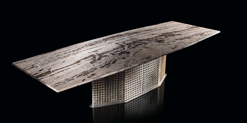 S-Penny Table, central legs structure of silver on brass creating a rhombus pattern, top in grey, black and white stone on a black background.
