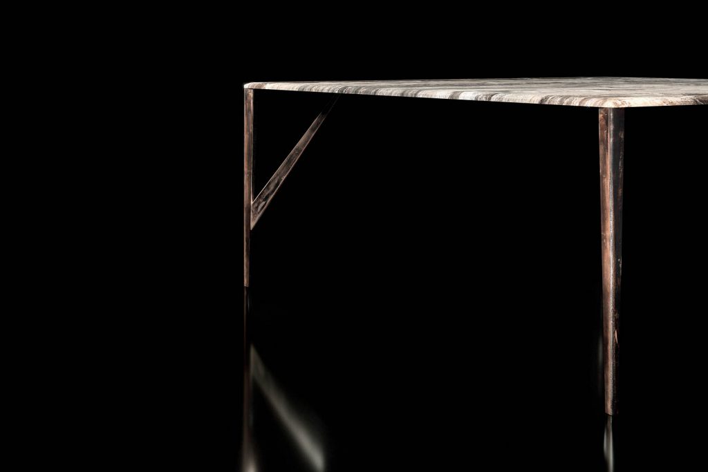 Square Saetta Table, four legs in sandlasting brass and bronze. Top in gray and black stone on a black background.