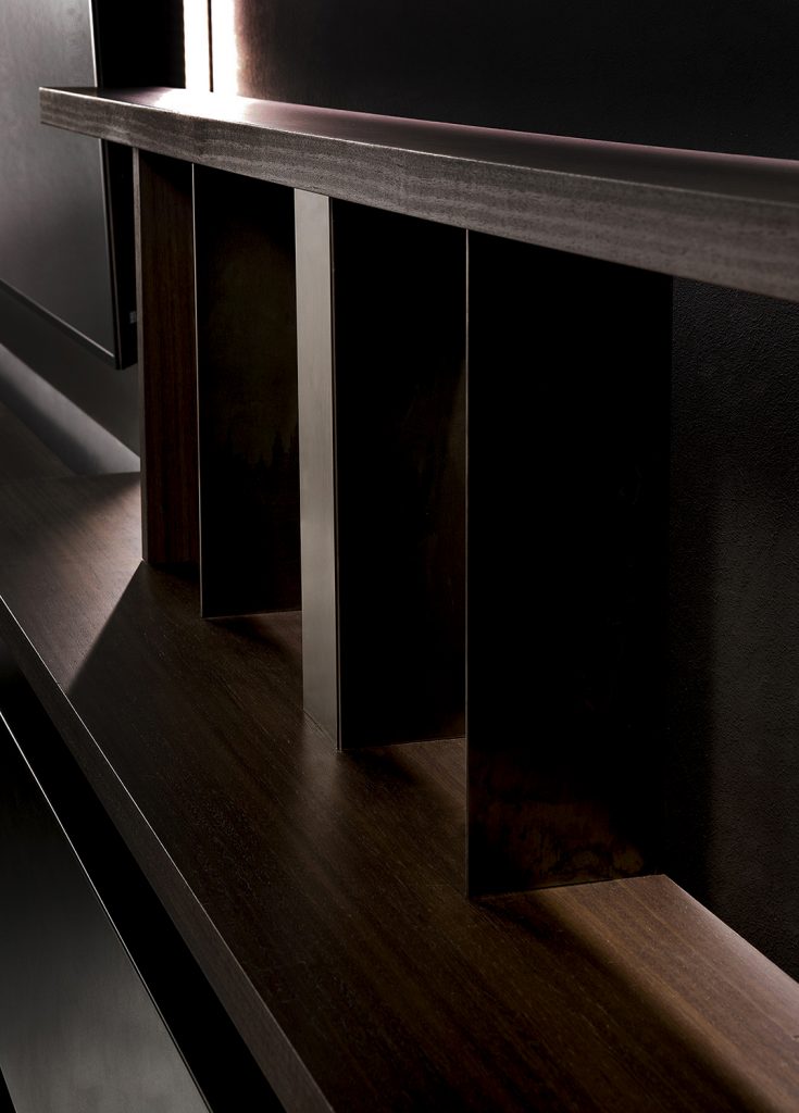 Closeup of Style Set bookcase, structure in natural wood color. Storage units, internal partitions and tv panel in burnished platino on a black background.