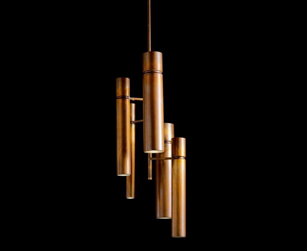Two Tubular Ceiling Lights with a cylindrical shape in bronze joined with bronze-colored metal bars suspended with a rope on a black background.