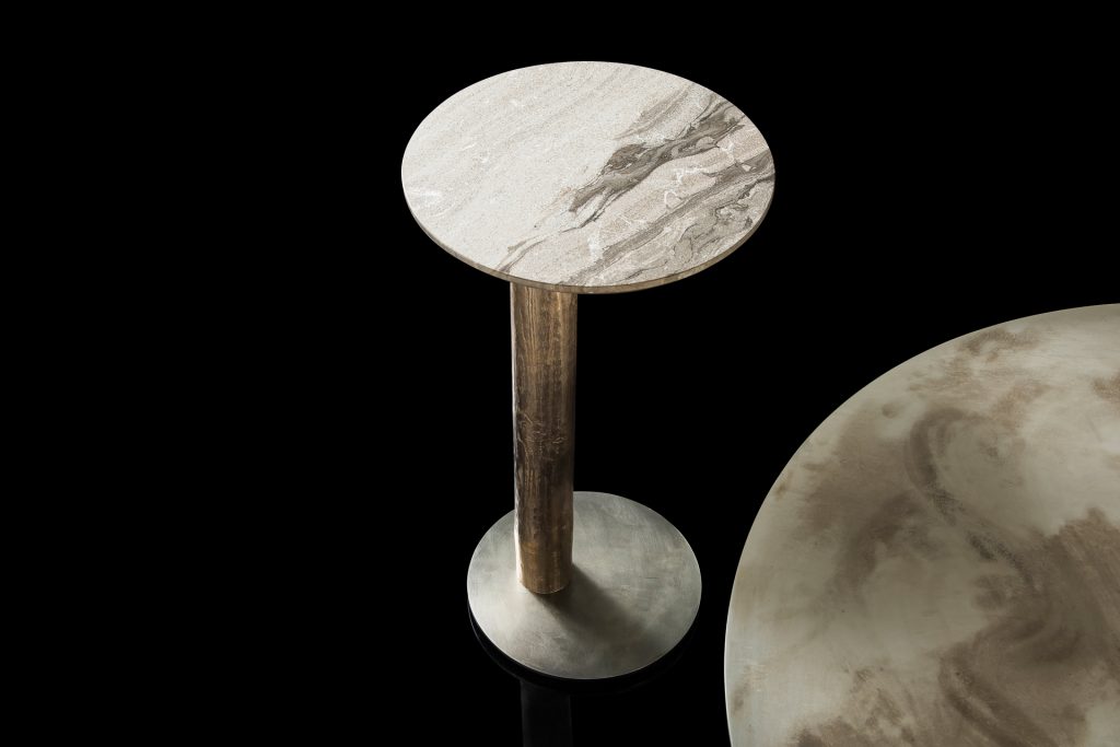 Round Twistable Coffe Table And Consolle. Structure support in silver, top in gray and white stone and central leg in burnished platino on a black background.
