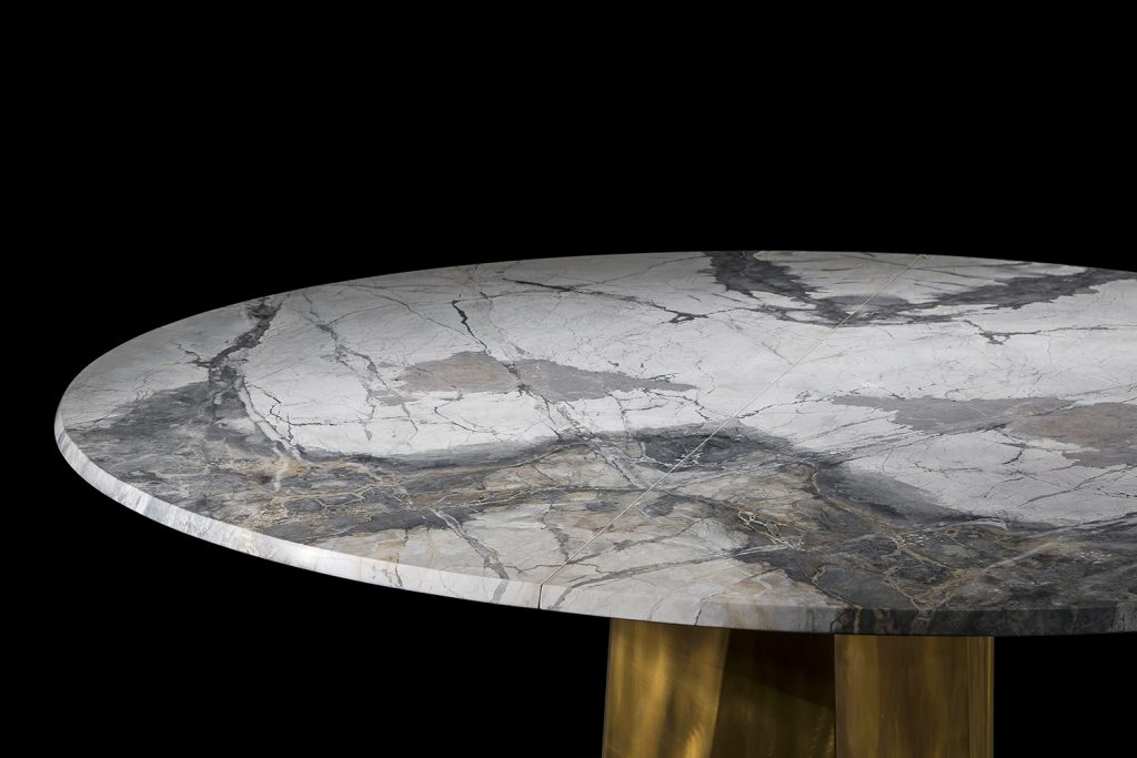 Zenith Table , white and black marble top, central leg in gold brass casing on a black background.