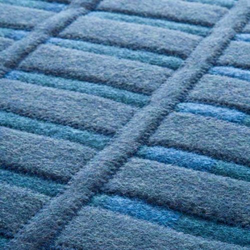 Accordi rug. The surface of the rug consists of blue anternated stripes and horizontal and vertical felt stripes.