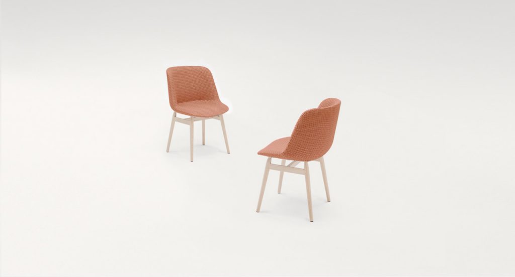 Two Adele Chairs with four natural wood legs, upholstered in pink fabric on a white background.