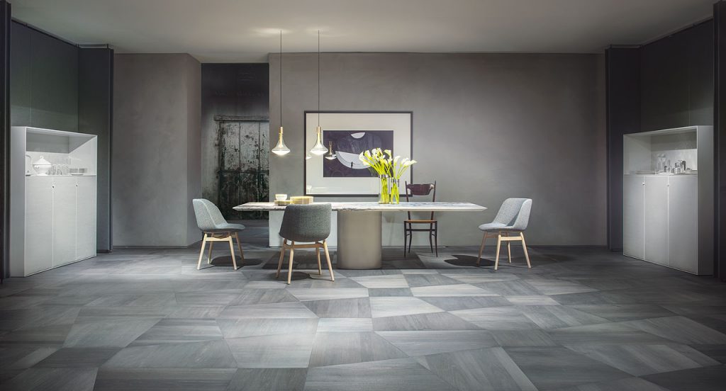 Three Adele Chairs with four black wood legs, upholstered in gray fabric in a dining room.