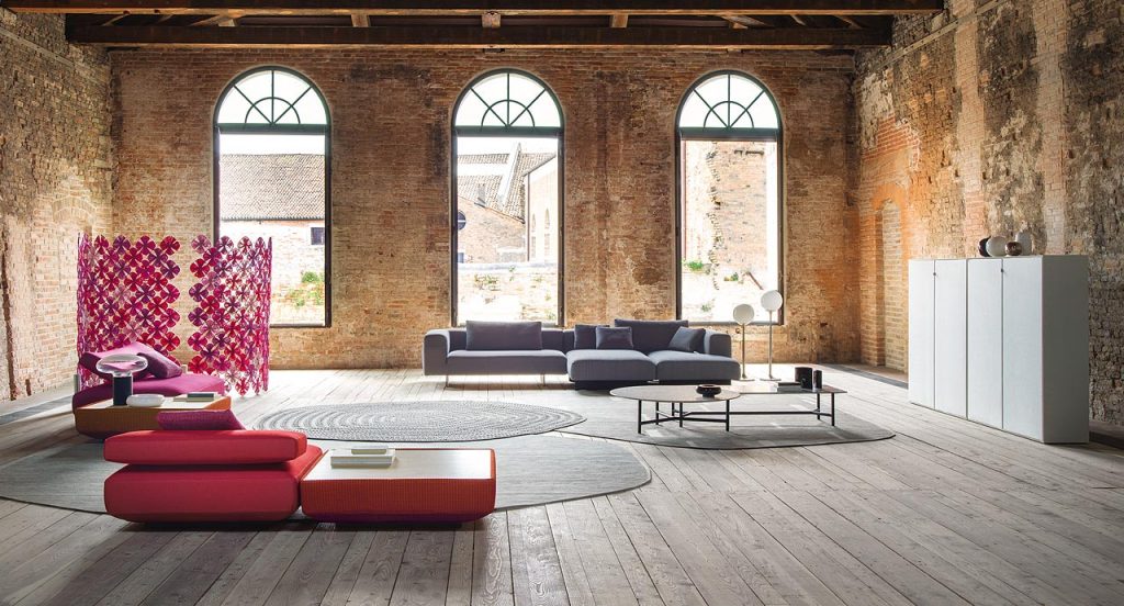 Atollo Next sofa and two modular elements, upholstery in grey fabric, legs in steel in a living room.