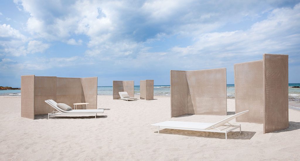 Six Abri corner and linear panels upholstered in natural thuia fabric on a beach.