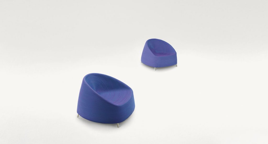 Two Afra Armchairs upholstered in blue purple cord sewn with a spiral-like pattern and four legs in steel on a white background.