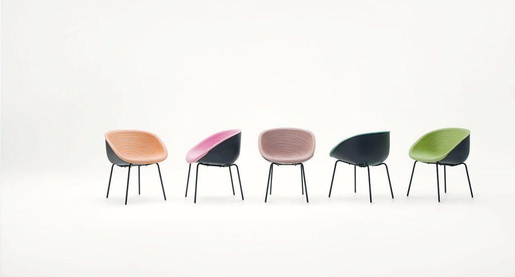 Five Amable Armchairs, four legs of white steel, black molded polyethylene shell and rope cord cover, three in pink and two in green on a white background.