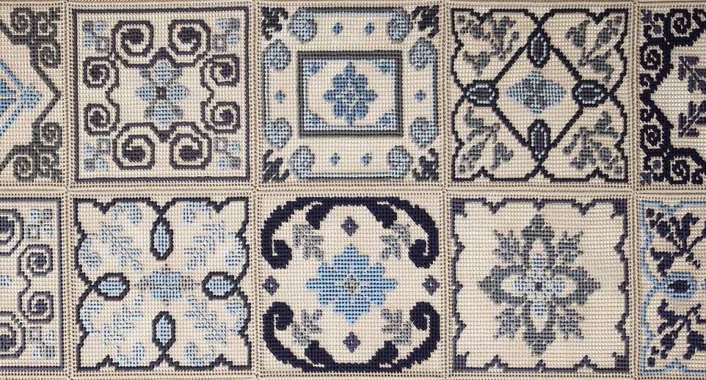 Donna Costanza rug embroidered with gray, blue, black and beige flat braids of abstract pattern.