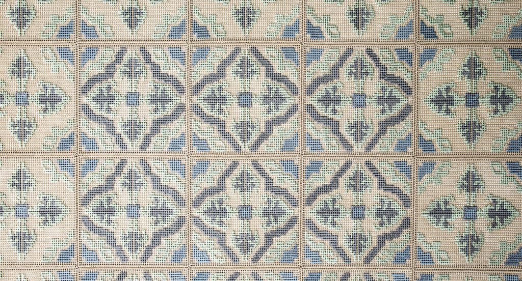 Donna Florio rug, embroidered with gray, blue, green and beige flat braids with a diamond like pattern.