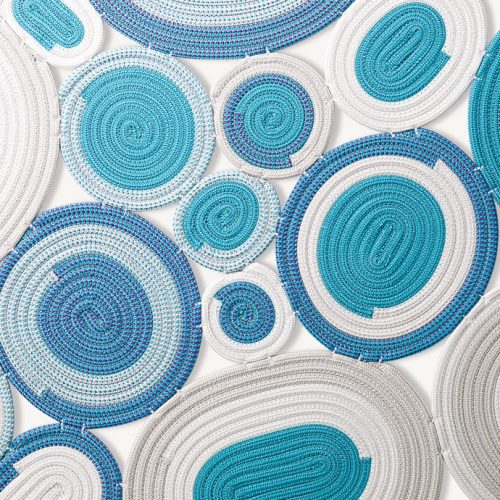Ellissi rug made of blue, white, grey and brown cords creating round and oval modules on a white background.