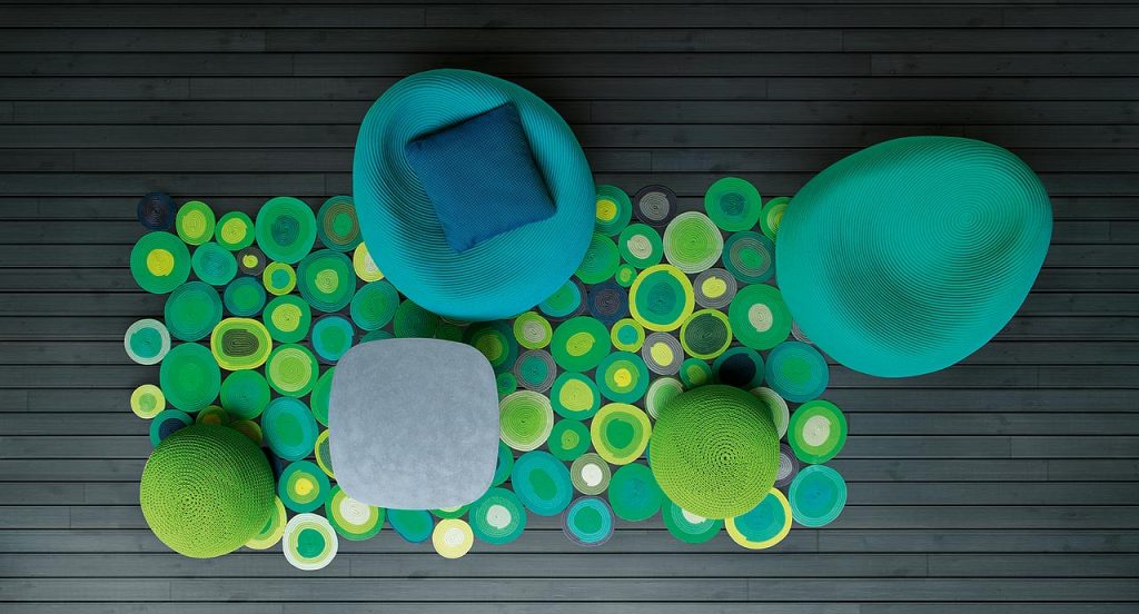 Ellissi rug made of yellow, green, blue, white and grey cords creating round and oval modules in a living room.