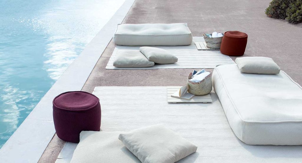 Two Float Outdoor Poufs, upholstery in white fabrics next to a pool.