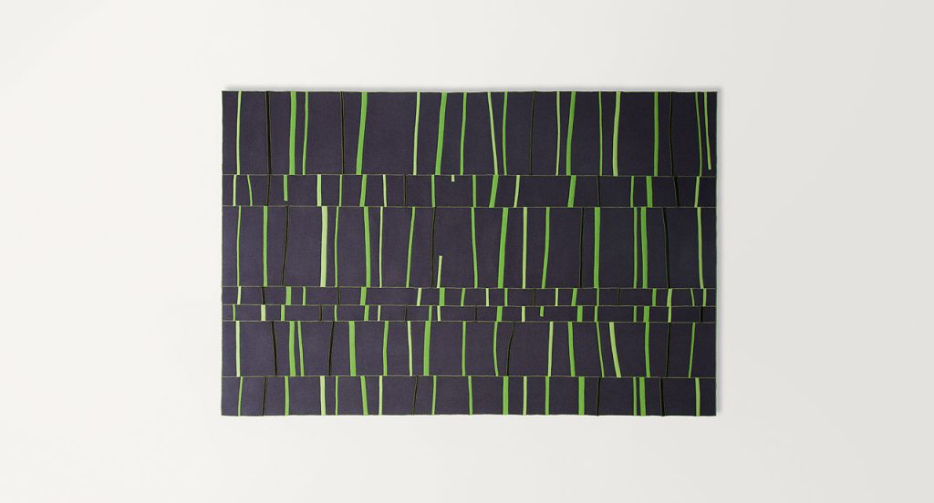 Graffito rug made of rectangles and strips in black and green felt on a white background.