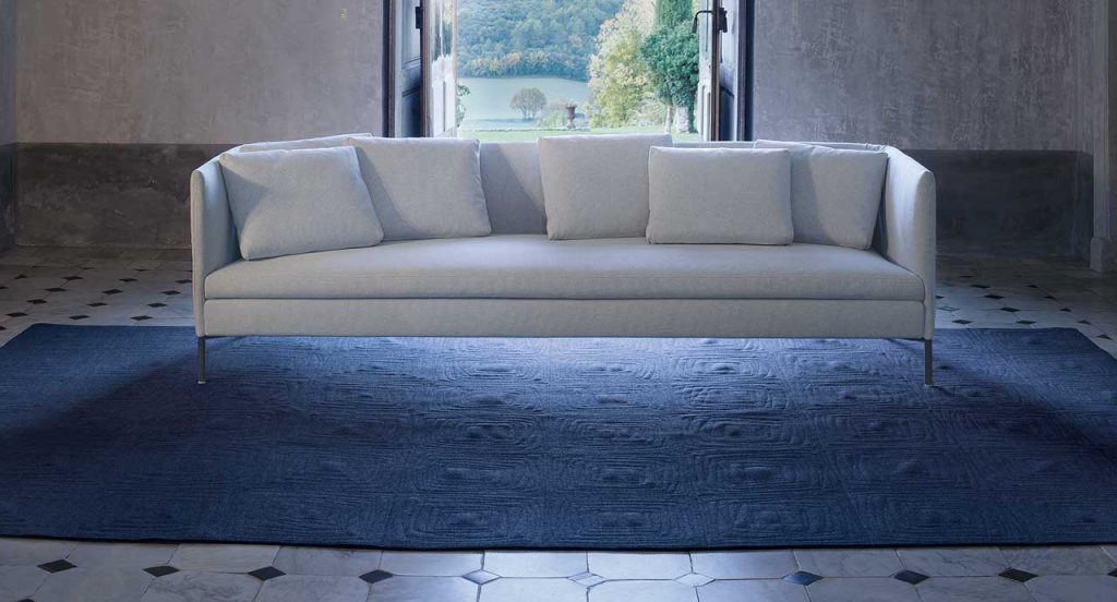 Imperfetto of blue square felt. The embroidery on each element creates an irregular squared spiral-like pattern in a living room.