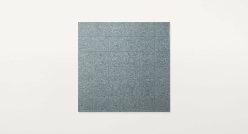 Imperfetto of blue square felt. The embroidery on each element creates an irregular squared spiral-like pattern on a white background.