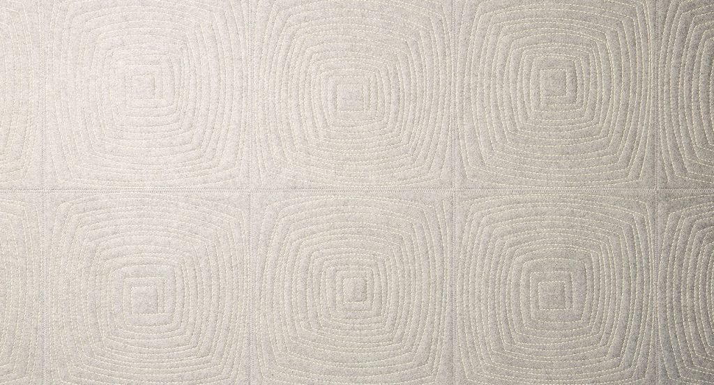 Imperfetto of beige square felt. The embroidery on each element creates an irregular squared spiral-like pattern.