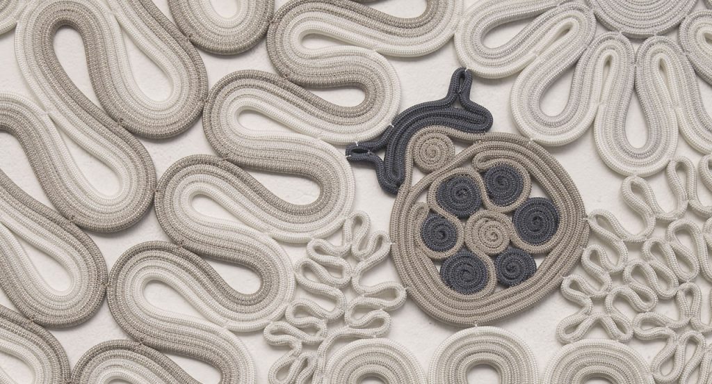 Ladybird rug, plants and animals like pattern in white, brown and grey on a white background.