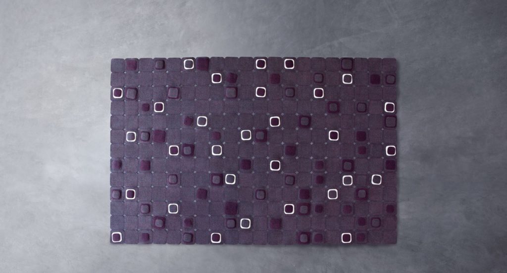 Pixel rug made with square felt elements in color purple and white on a grey background.