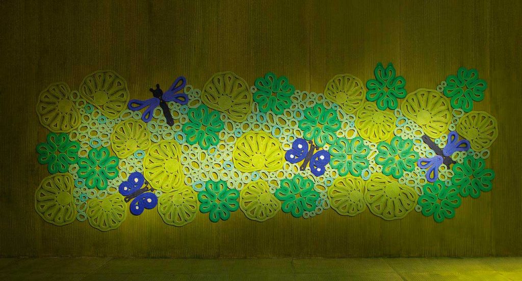 Pond rug, plants and animals pattern in green, yellow, white, blue, brown made in rope cords on a brown floor.