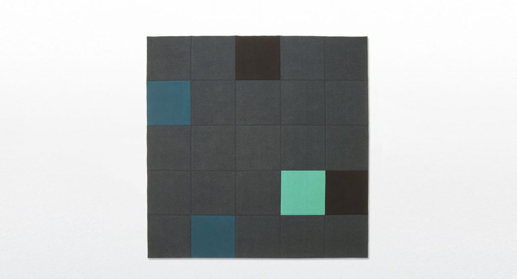Quadri Double in grey, black, blue and green square felt modules on a white background.