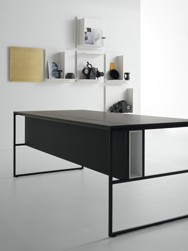 A 20 Venti workstation single desk. Black tops are made of medium density fibreboard panels, in has a structural wireway, Steel frame and legs in graphite grey and open compartment in a office.