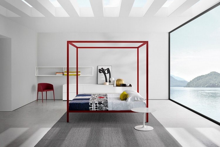 A red Achille Armchair In metal tubing, foamed with polyurethane rubbers, upholstered with fabric in a bed room.