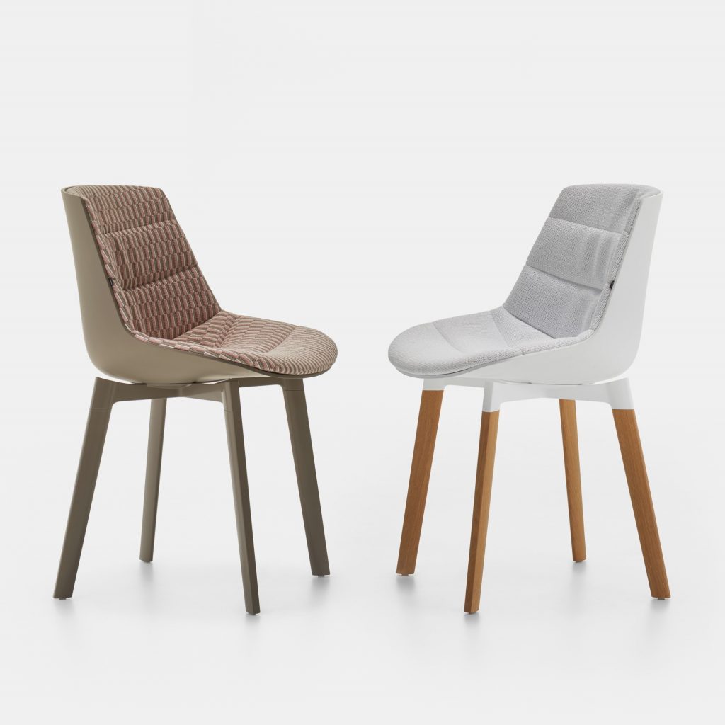 Two Flow Chairs Padded, one color white with natural wooden bottom and one color with a coffee bottom on a office background.