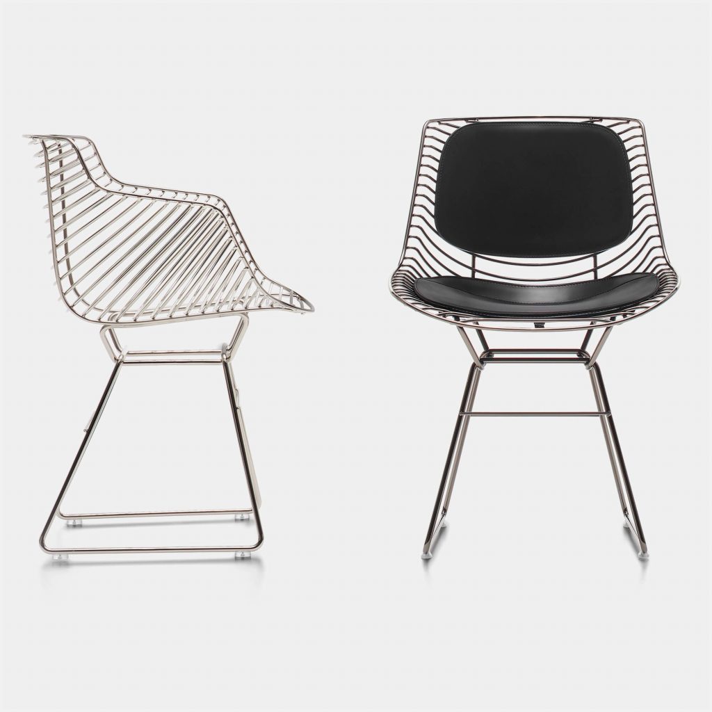 Two Flow Milo chairs made of steel core in black chrome finish, one with a black leather padding covering and backrest on a white background room.