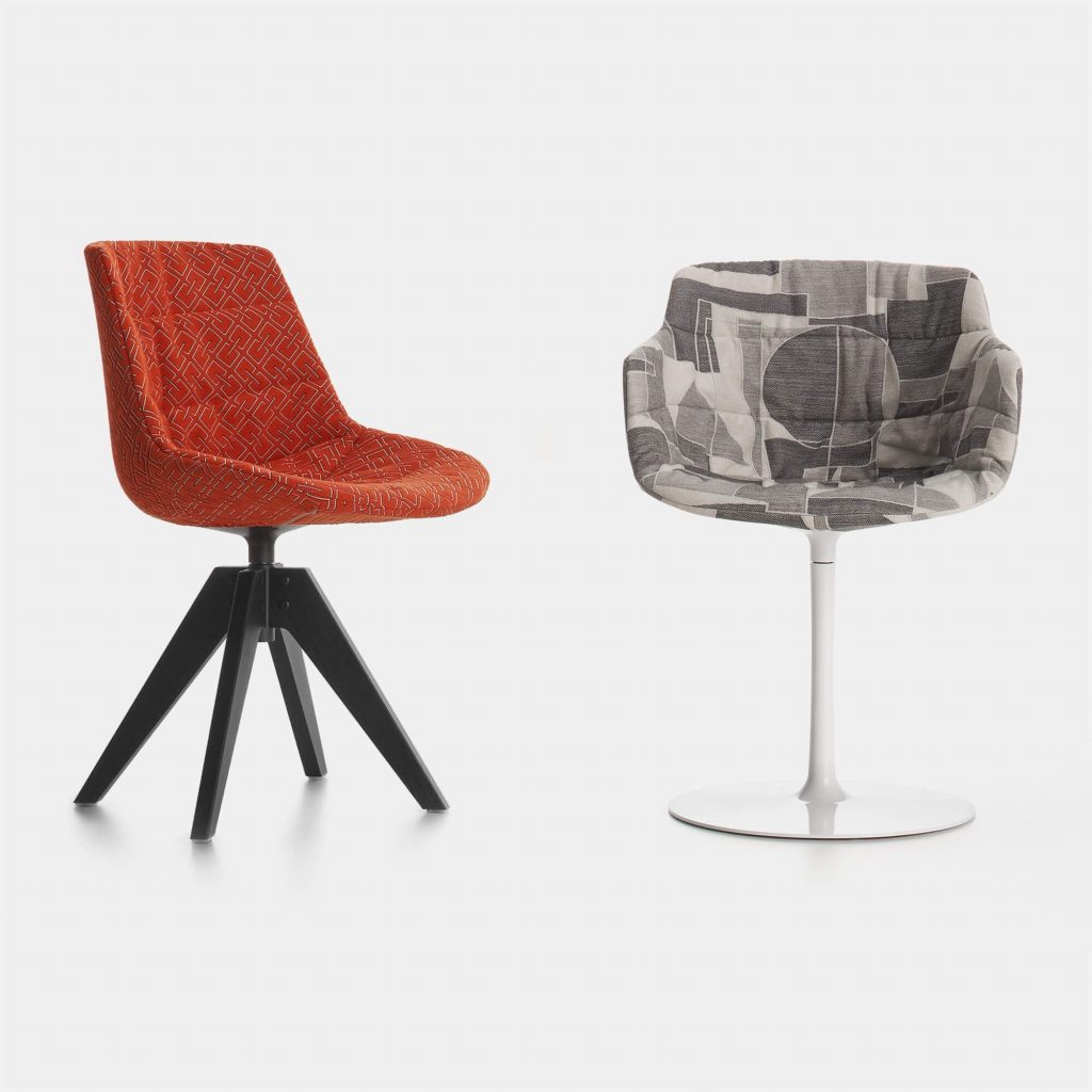 Two Flow Textile chairs, one in orange pattern with four-legged in black steel, one in grey pattern with a white central leg on a white background.