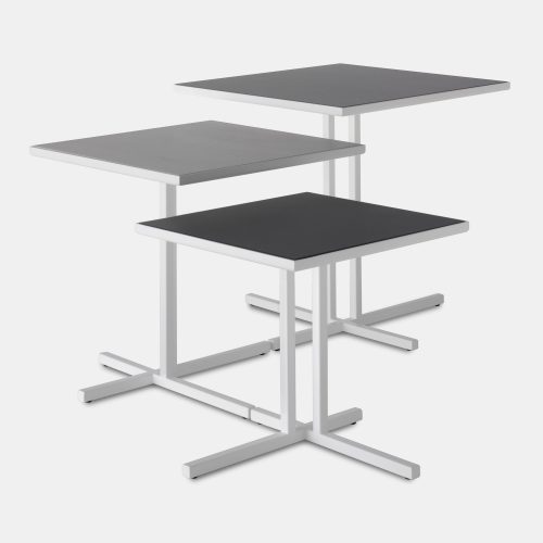 Three K Tables, tabletops in dark grey ceramic and frames in white steel on a white background.