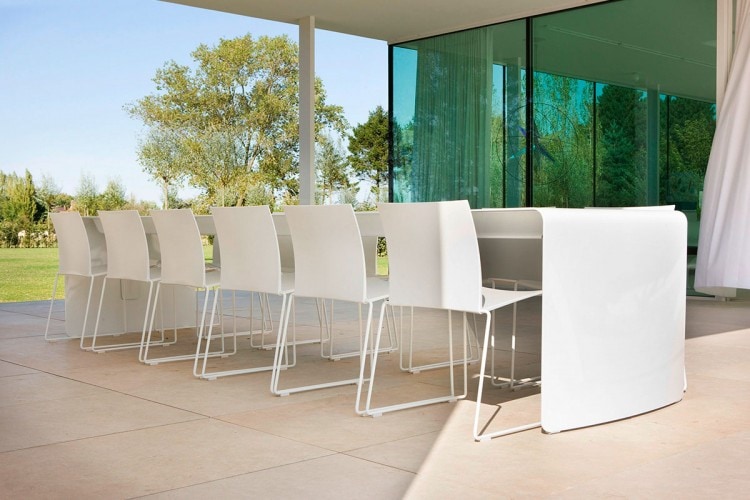One La Grande Table made with a curved aluminium sheet. Finish in gloss white lacquered on a outdoor room background.