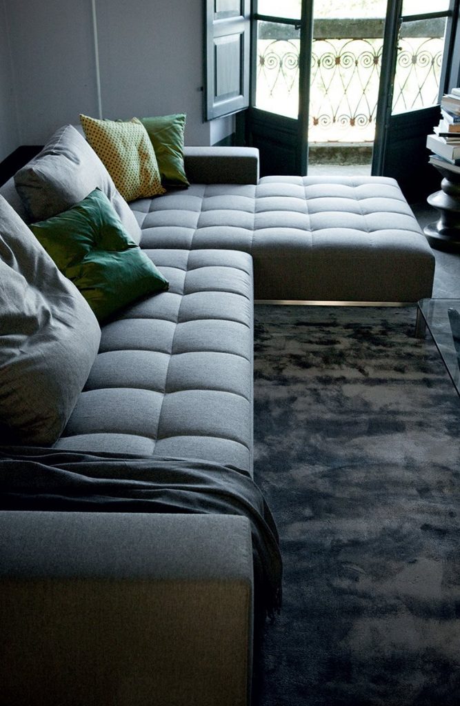 L shaped Alfa sofa with a rectangular black seat and backrest, featuring silver legs in a living room.