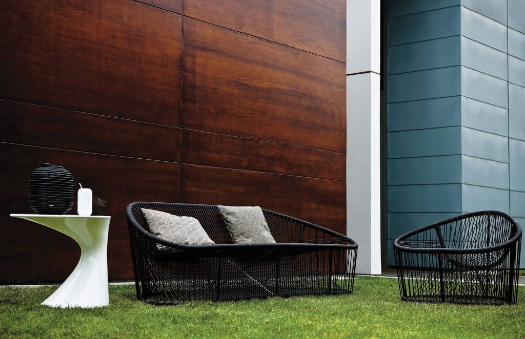 Club armchair, seat, backrest and frame in brown metal in a garden.