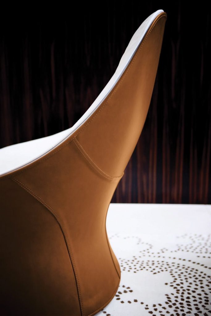 Closeup of Derby armchair upholstered seat and backrest in white and brown in a living room.