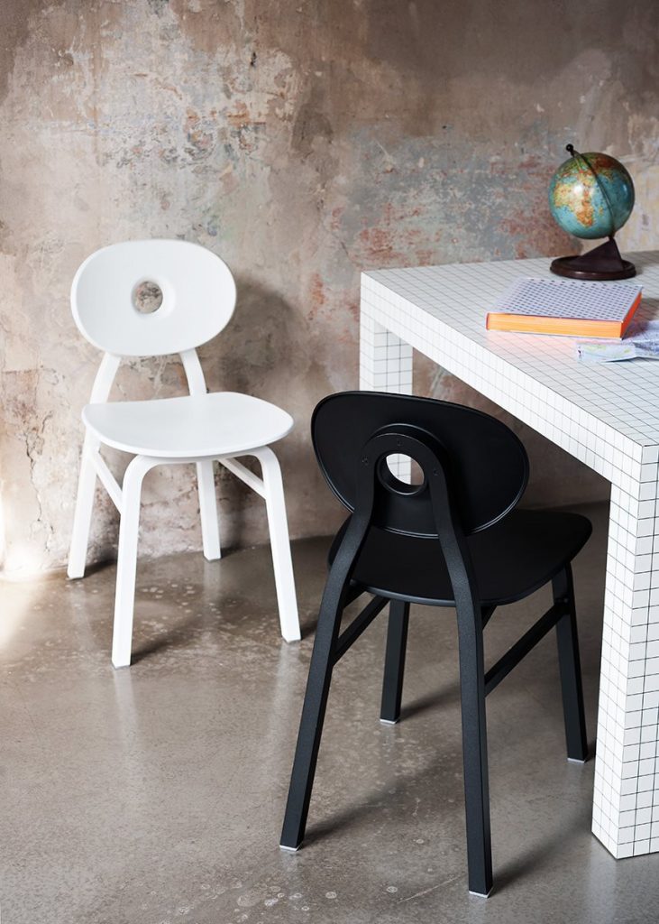 Two Elipse chairs, one in black and one in white with round back with four legs in a dining room.