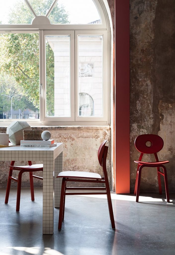 Three Elipse chairs in red with round back with four legs in a dining room.
