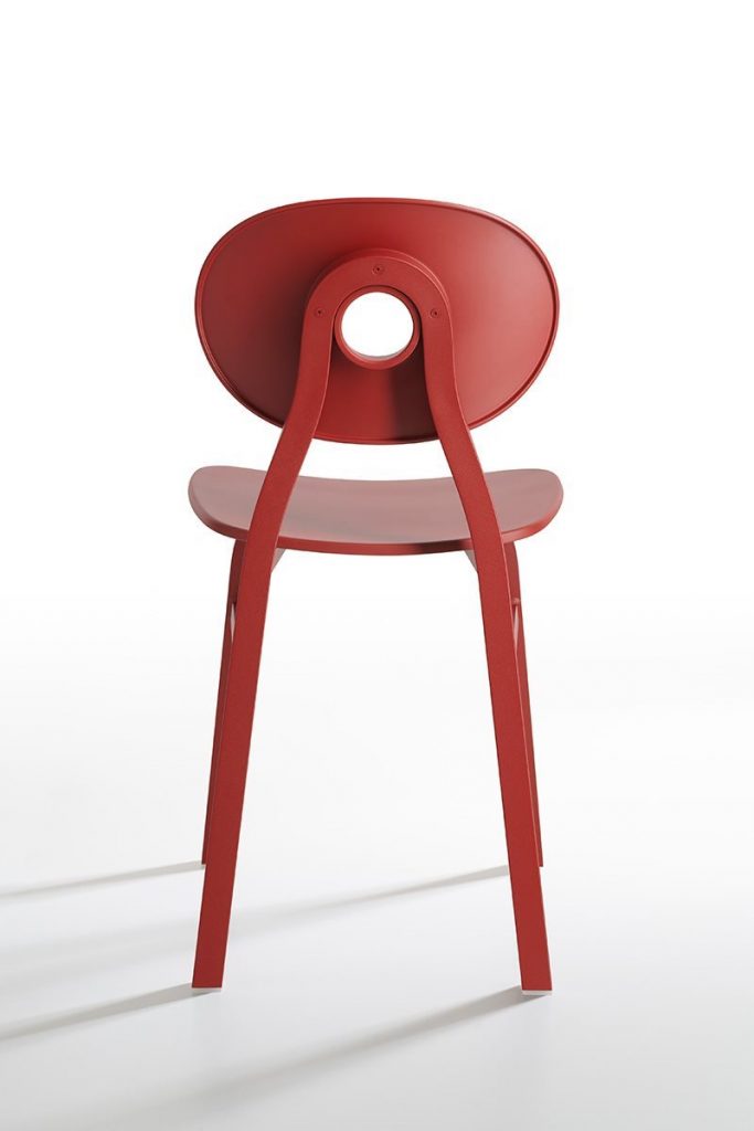 Elipse chair in red with a round back with four legs on a white background.