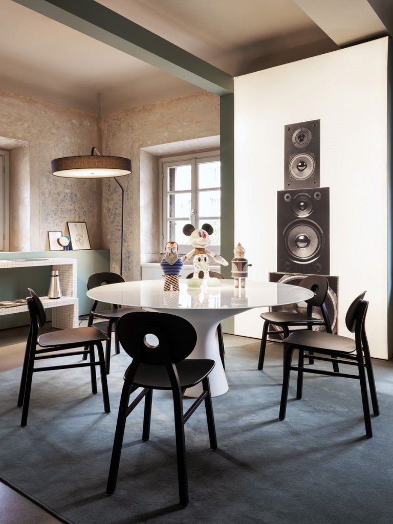 Five Elipse chairs, one in black with round back with four legs in a dining room.
