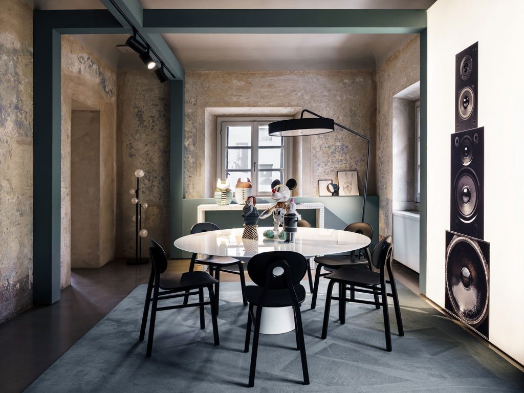 Five Elipse chairs, one in black with round back with four legs in a dining room.