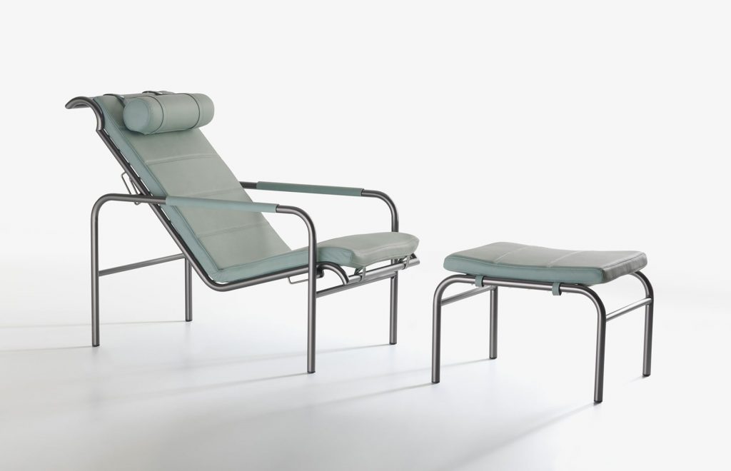 Genni lounge chair with a contemporary design, featuring a wide, green cushioned seat, a metal frame and stool on a white background.