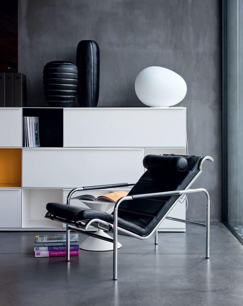 Genni lounge chair with a contemporary design, featuring a wide, black cushioned seat and a metal frame in a living room.