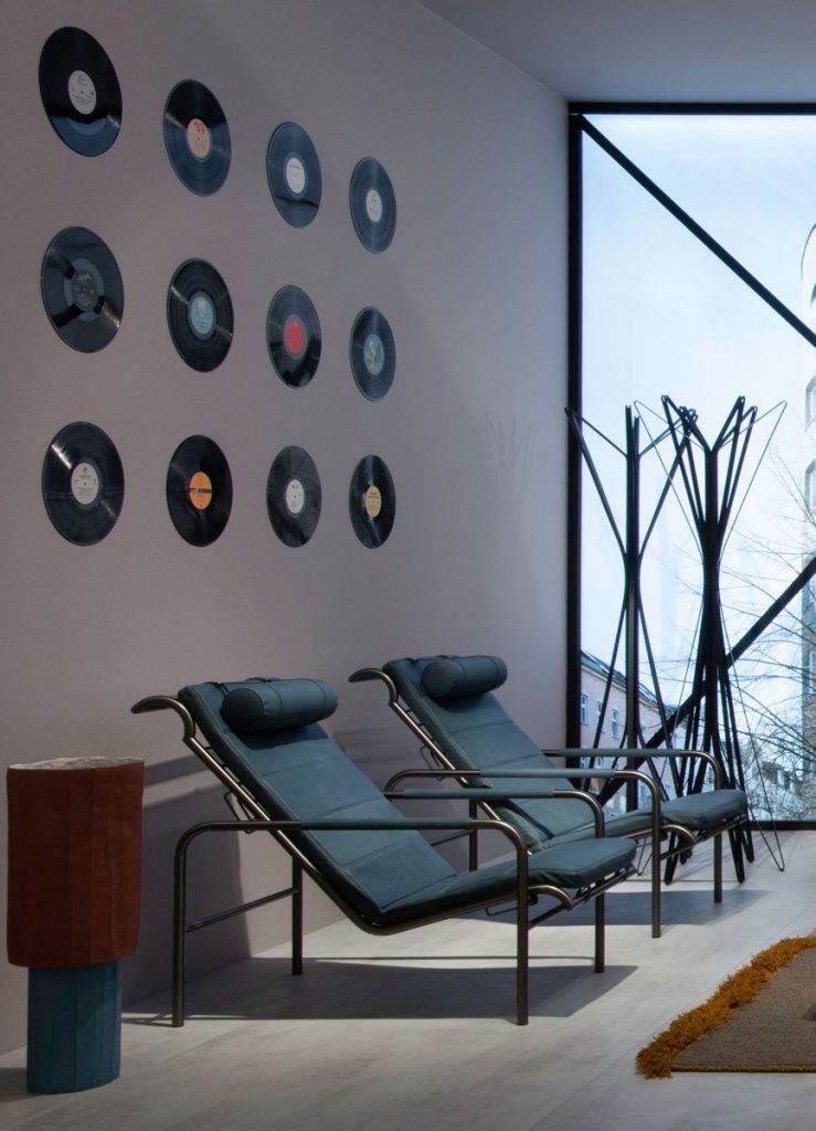 Two Genni lounge chairs with a contemporary design, featuring a wide, black cushioned seat and a metal frame in a living room.