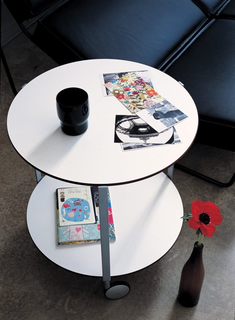 Giro table with white round top and base and three metal structure legs in a living room.