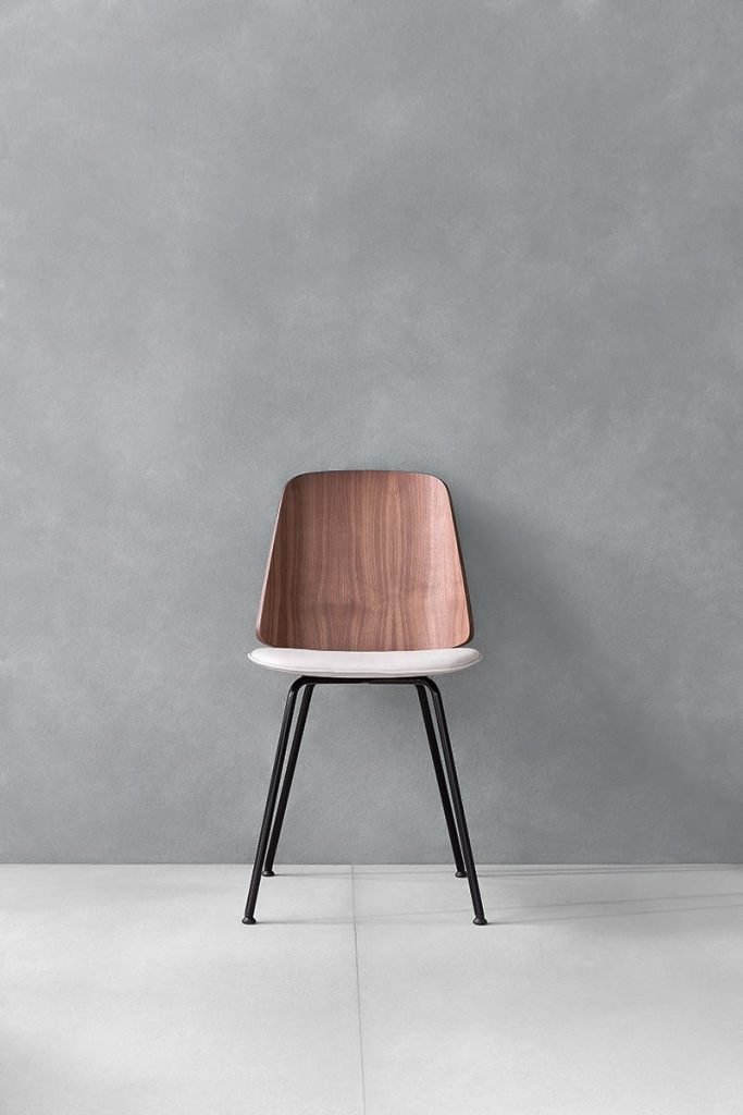 June chair with a white cushioned seat and natural wood backrest on a gray background.