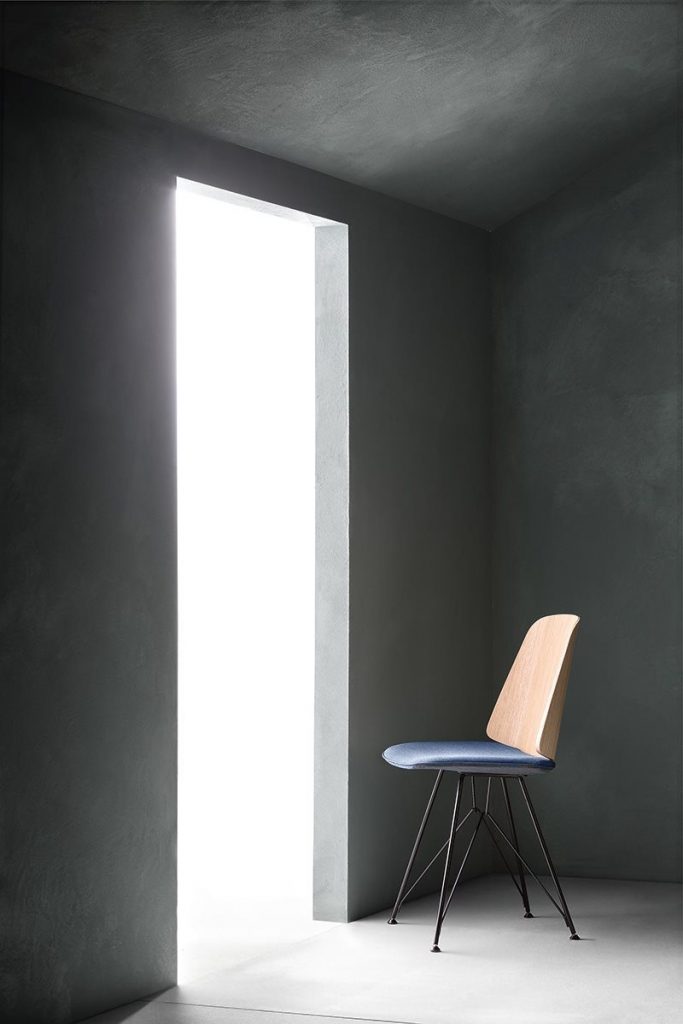 June chair with a blue cushioned seat and natural wood backrest on a gray background.