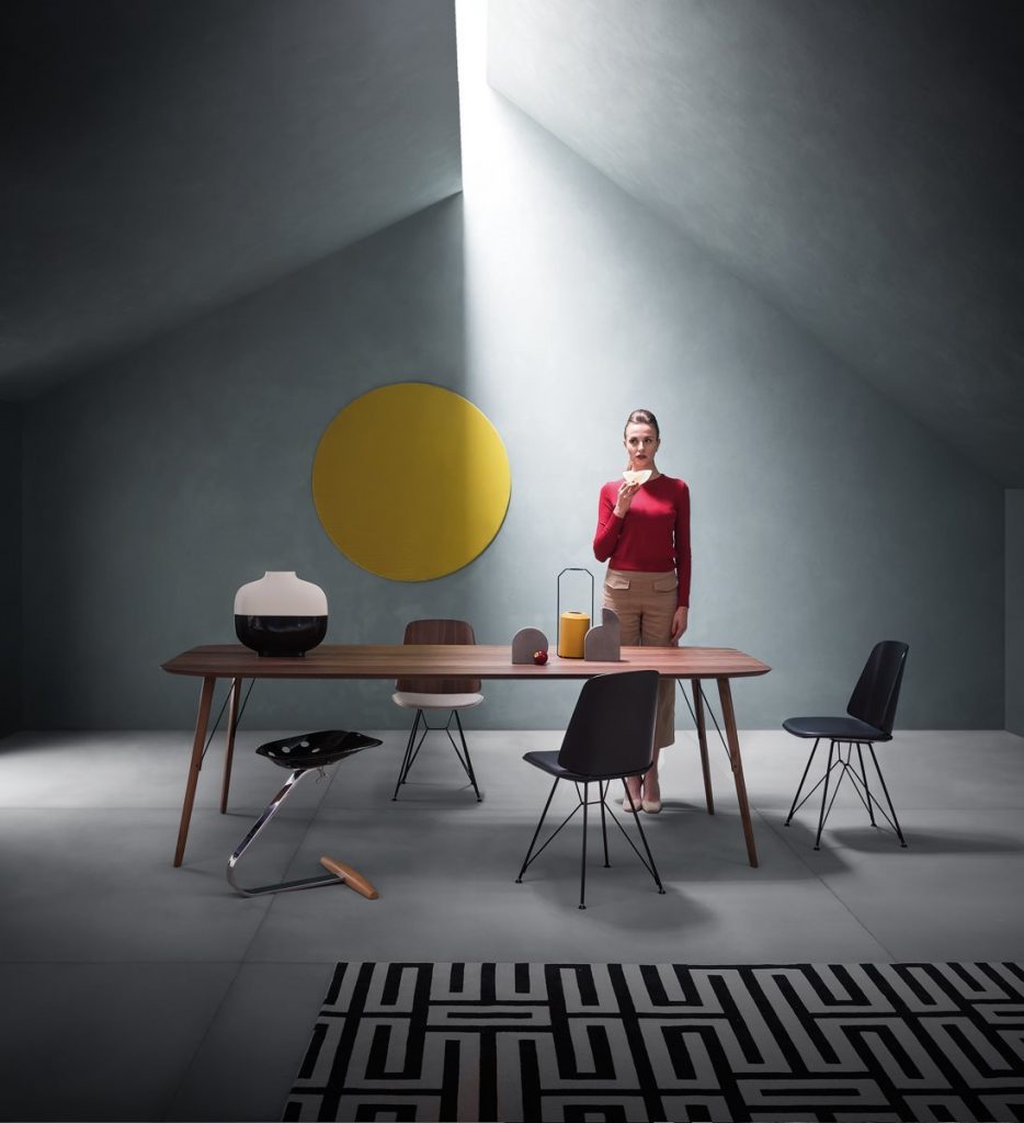 Mezzadro black stool with a unique design, featuring a red seat on a chrome base in a living room.